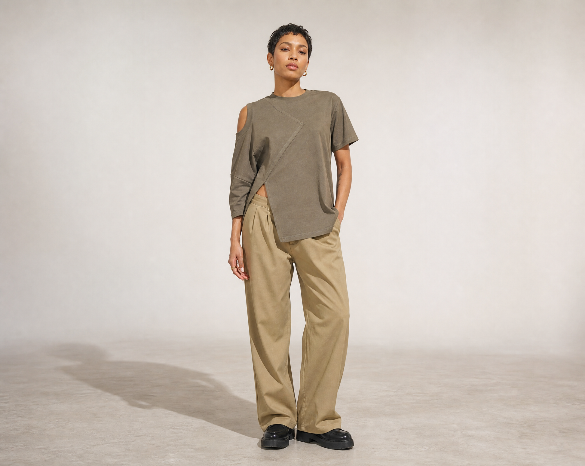 Person wearing a Mesan green oversized shirt and beige pants on a plain background